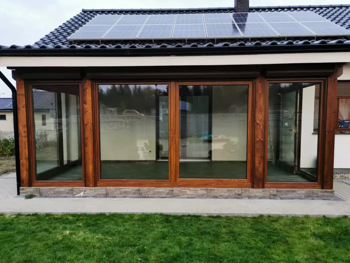 Große Fensterfront mit Holzrahmen an einem Wintergarten